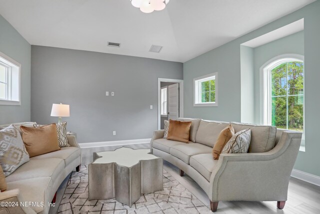 living room featuring light wood-type flooring, visible vents, and baseboards