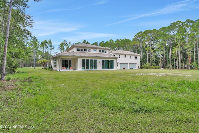 back of property with a garage and a yard