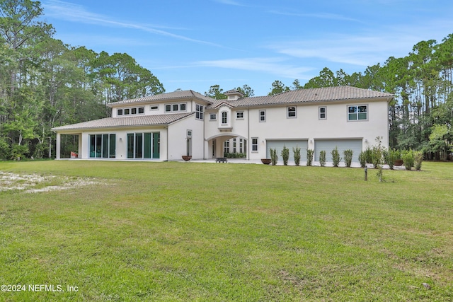 back of house with a garage, a tile roof, a yard, and stucco siding