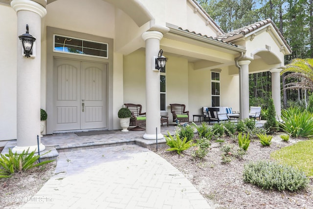 property entrance featuring a tile roof, a porch, and stucco siding