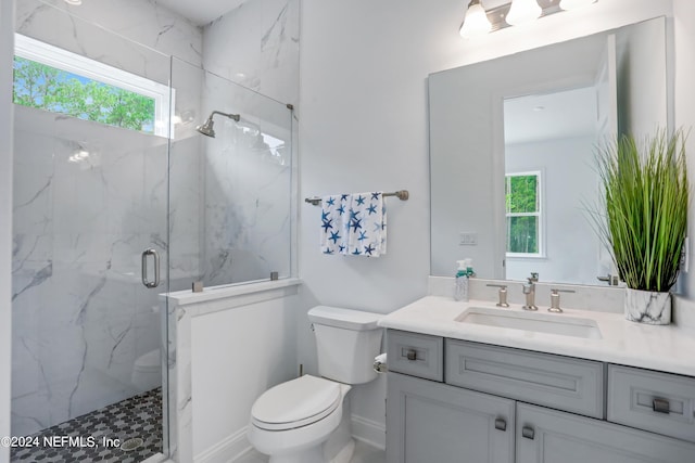 full bathroom featuring baseboards, toilet, vanity, and a marble finish shower