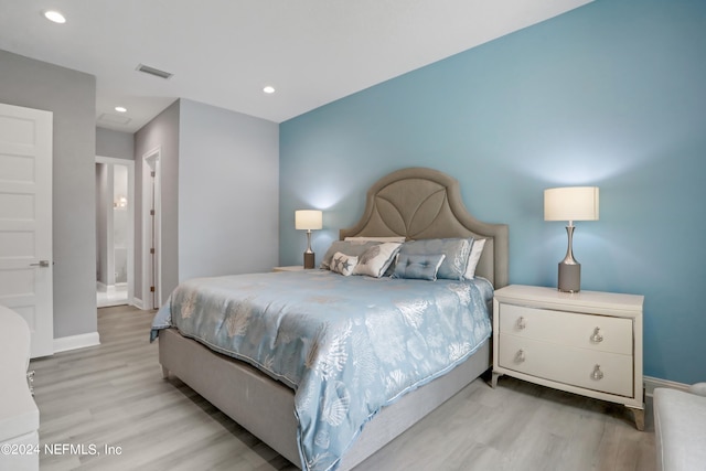 bedroom featuring ensuite bath and light hardwood / wood-style flooring