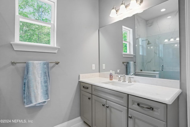 bathroom featuring baseboards, vanity, and a marble finish shower