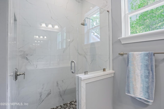 full bath featuring a marble finish shower and a wealth of natural light