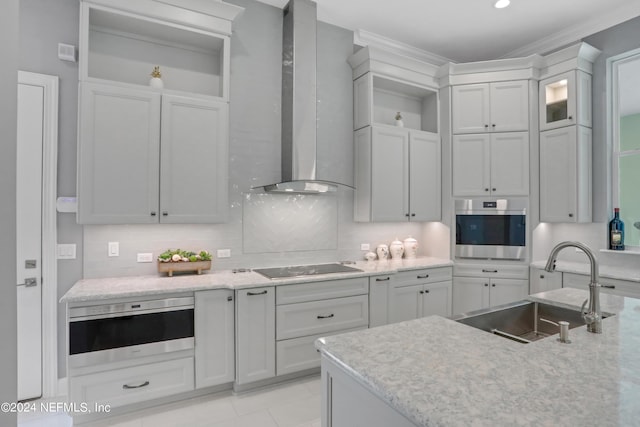 kitchen with wall chimney exhaust hood, stainless steel oven, tasteful backsplash, and a sink