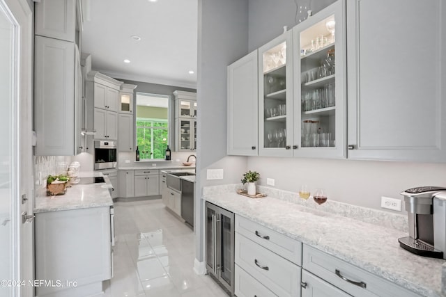 kitchen with light stone counters, stainless steel appliances, beverage cooler, white cabinets, and light tile patterned flooring