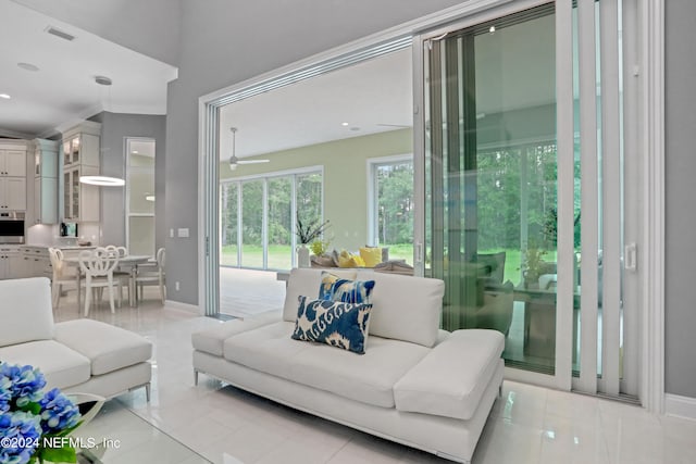 living room with ceiling fan, light tile patterned floors, and ornamental molding