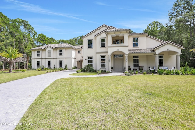 mediterranean / spanish home with a tile roof, a front lawn, decorative driveway, and stucco siding