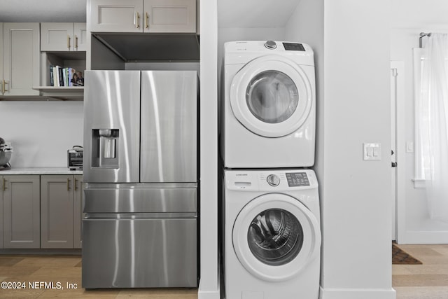 washroom with stacked washer / drying machine and light wood-type flooring