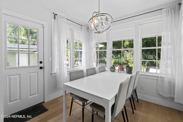 dining room with an inviting chandelier, a wealth of natural light, and light hardwood / wood-style flooring