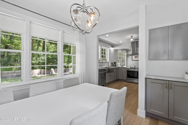 dining area with light hardwood / wood-style flooring, a wealth of natural light, a notable chandelier, and sink