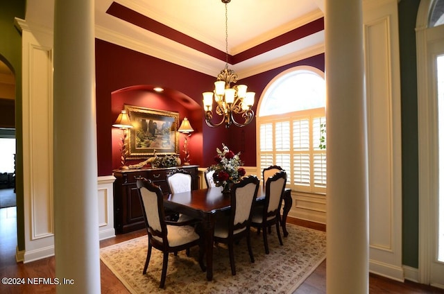 dining area with decorative columns, dark wood-type flooring, crown molding, and an inviting chandelier