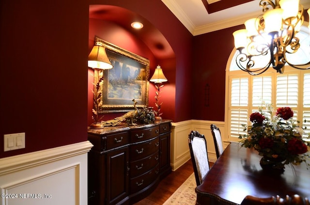 dining space with dark wood-type flooring, crown molding, and an inviting chandelier