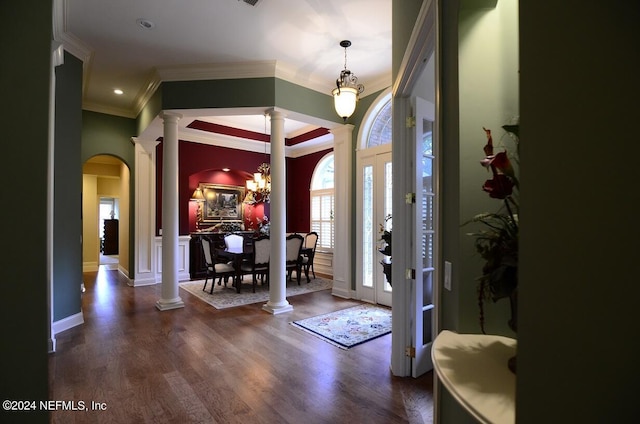 entrance foyer with an inviting chandelier, ornamental molding, dark hardwood / wood-style flooring, and decorative columns