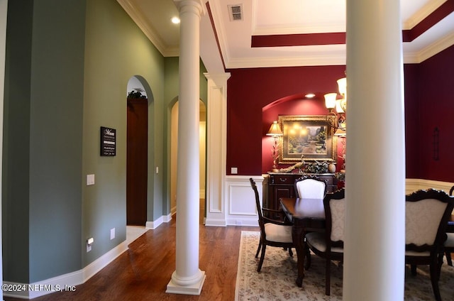 hallway with wood-type flooring, an inviting chandelier, ornamental molding, and decorative columns