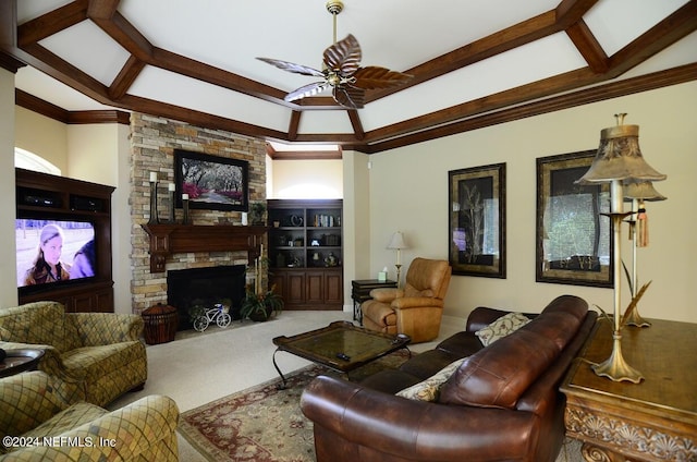 living room featuring built in shelves, a stone fireplace, carpet flooring, ceiling fan, and crown molding