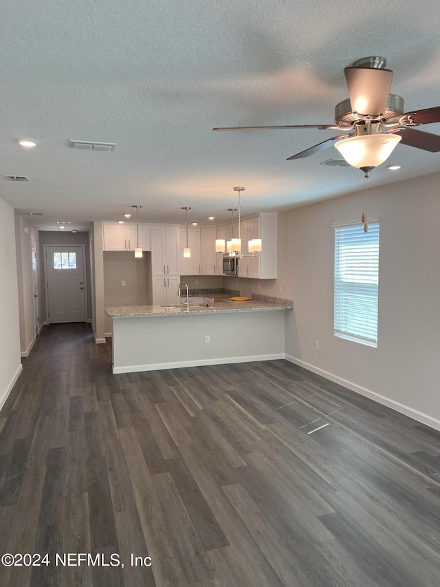 kitchen with white cabinets, decorative light fixtures, kitchen peninsula, and dark wood-type flooring