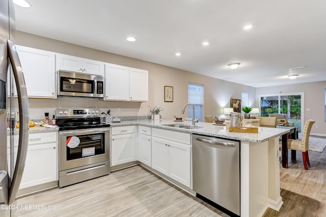 kitchen with sink, kitchen peninsula, light hardwood / wood-style floors, white cabinets, and appliances with stainless steel finishes