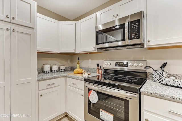 kitchen featuring light stone countertops, appliances with stainless steel finishes, hardwood / wood-style flooring, and white cabinetry