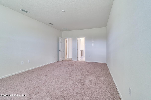 spare room with visible vents, light carpet, baseboards, and a textured ceiling