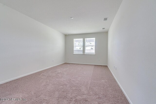 unfurnished room with light carpet, a textured ceiling, visible vents, and baseboards