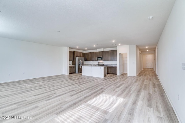 unfurnished living room featuring recessed lighting, baseboards, a textured ceiling, and light wood finished floors