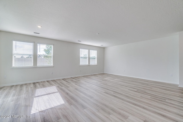 empty room featuring light wood-type flooring and a textured ceiling