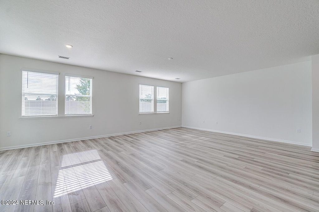 7882 Rippa Valley Way, Jacksonville, FL 32222 - empty room with light wood-style flooring, a textured ceiling, visible vents, and baseboards