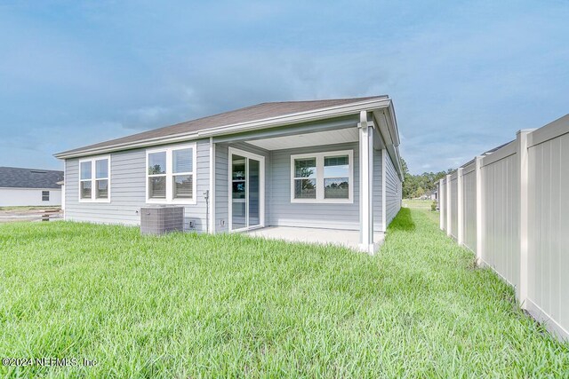 back of property with central AC unit and a lawn