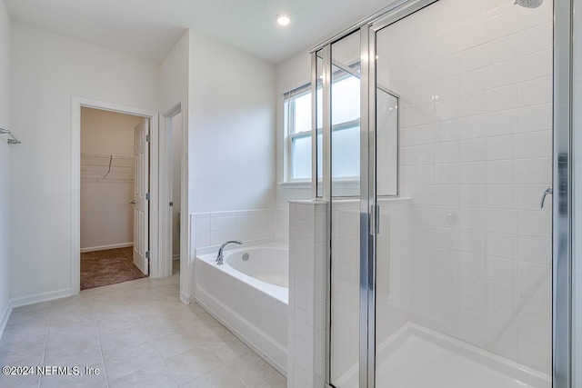 full bathroom featuring a stall shower, baseboards, a garden tub, tile patterned flooring, and a spacious closet