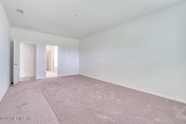 unfurnished bedroom with light carpet, a textured ceiling, visible vents, and baseboards
