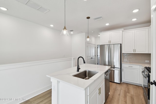 kitchen with white cabinetry, sink, a center island with sink, and decorative light fixtures