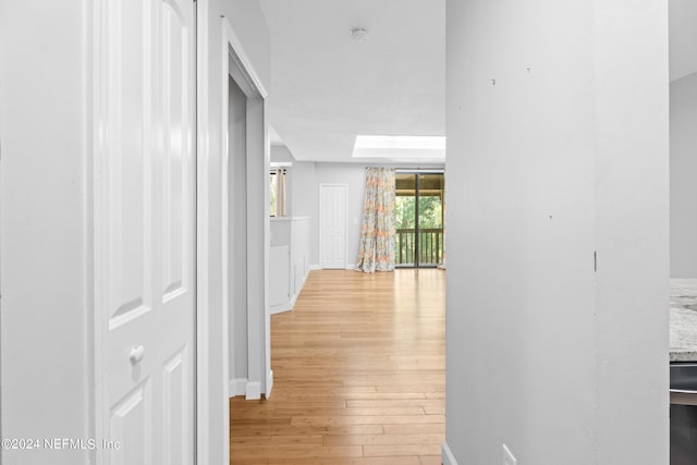 hallway with a skylight and light hardwood / wood-style flooring