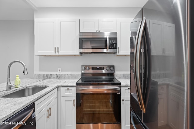 kitchen with white cabinets, light stone counters, sink, and stainless steel appliances