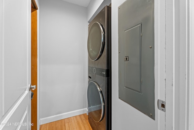 laundry area featuring electric panel, light hardwood / wood-style floors, and stacked washer / dryer