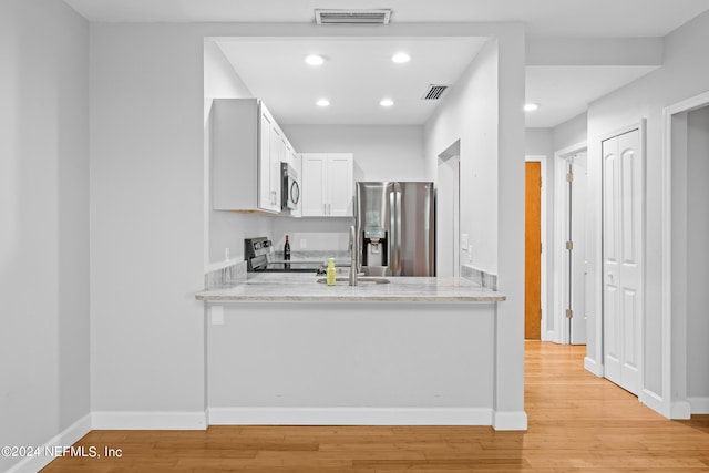 kitchen featuring light stone countertops, appliances with stainless steel finishes, sink, light hardwood / wood-style flooring, and white cabinetry