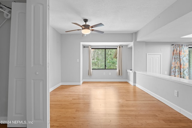 empty room featuring a textured ceiling, light hardwood / wood-style flooring, and ceiling fan