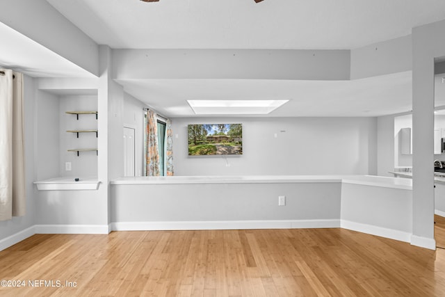 spare room with a skylight and light hardwood / wood-style floors