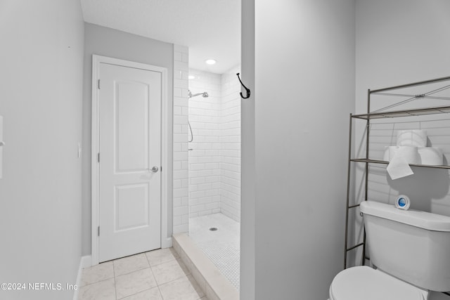 bathroom with toilet, tile patterned flooring, a textured ceiling, and tiled shower