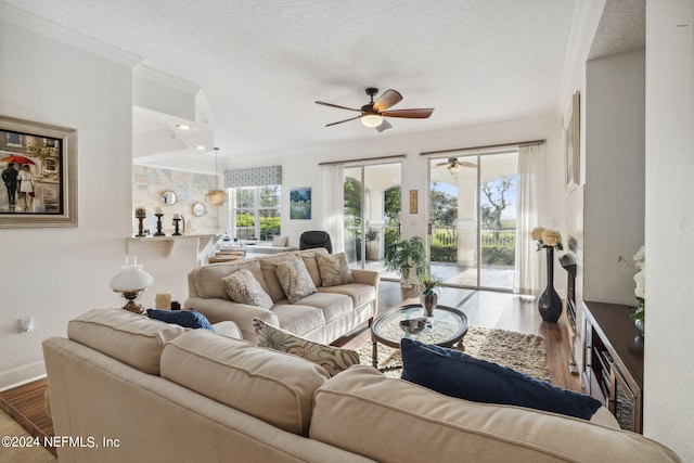 living room featuring wood-type flooring, a textured ceiling, ceiling fan, and ornamental molding