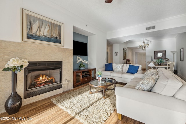 living room with ornamental molding, a chandelier, a textured ceiling, and hardwood / wood-style flooring