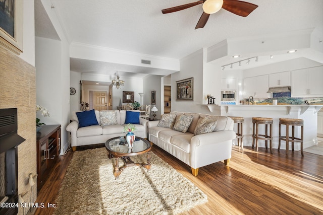 living room featuring ceiling fan, dark hardwood / wood-style flooring, a textured ceiling, and crown molding