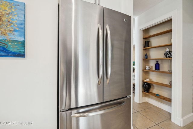 kitchen featuring white cabinetry, light tile patterned floors, and stainless steel refrigerator