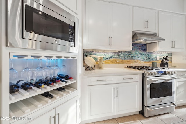 kitchen with backsplash, light tile patterned floors, range hood, white cabinetry, and stainless steel appliances