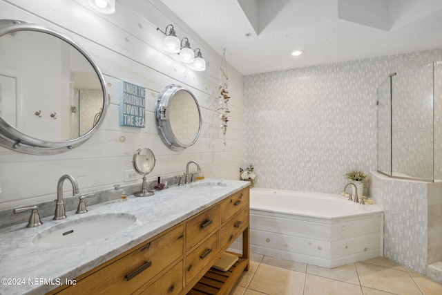 bathroom with tile patterned floors, a relaxing tiled tub, a textured ceiling, and vanity