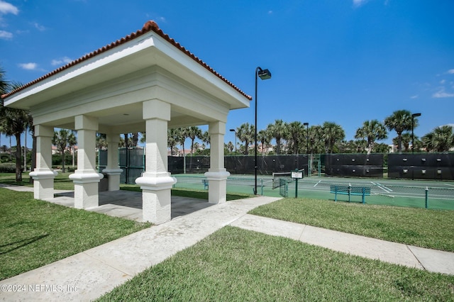 view of home's community with a yard and tennis court