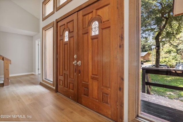 entryway with vaulted ceiling, a healthy amount of sunlight, and light wood-type flooring