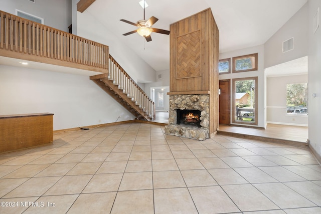 unfurnished living room featuring light tile patterned flooring, a stone fireplace, ceiling fan, and high vaulted ceiling