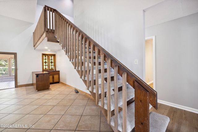 stairs with tile patterned flooring and a towering ceiling