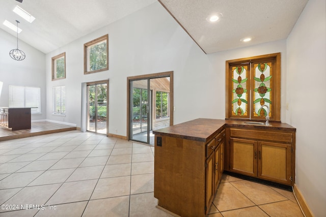 kitchen with a skylight, kitchen peninsula, sink, and light tile patterned floors